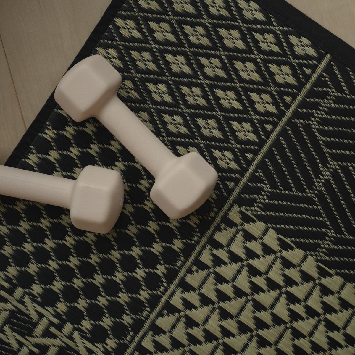 Bovenaanzicht van de Japanse Tatami Yogamat "Ed Plain" Zwart met dumbbells voor een stijlvolle yoga-opstelling thuis.