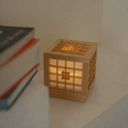 Lit Japanese Wood Table Lamp "Honoka" emitting a warm glow next to books, serving as a cozy cordless accent lamp.