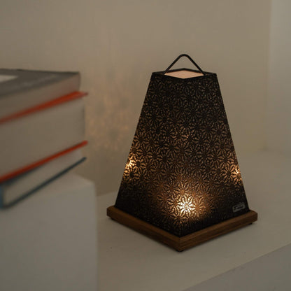 Glowing Japanese paper table lamp "Mini Akari" Black serving as a cozy paper lamp accent next to books on a Japandi living room shelf.
