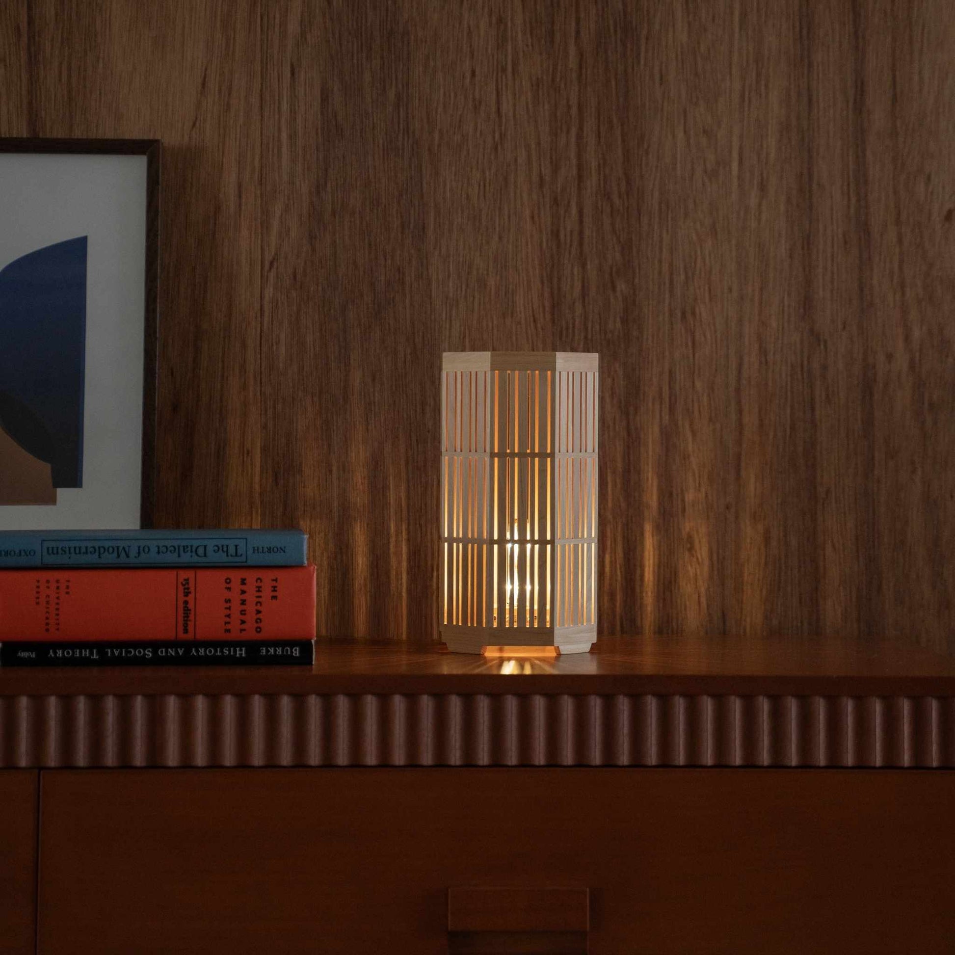 Glowing Japanese wood table lamp "Kagayaki" serving as a warm accent lamp on a wooden console in a mid-century modern living room setting.
