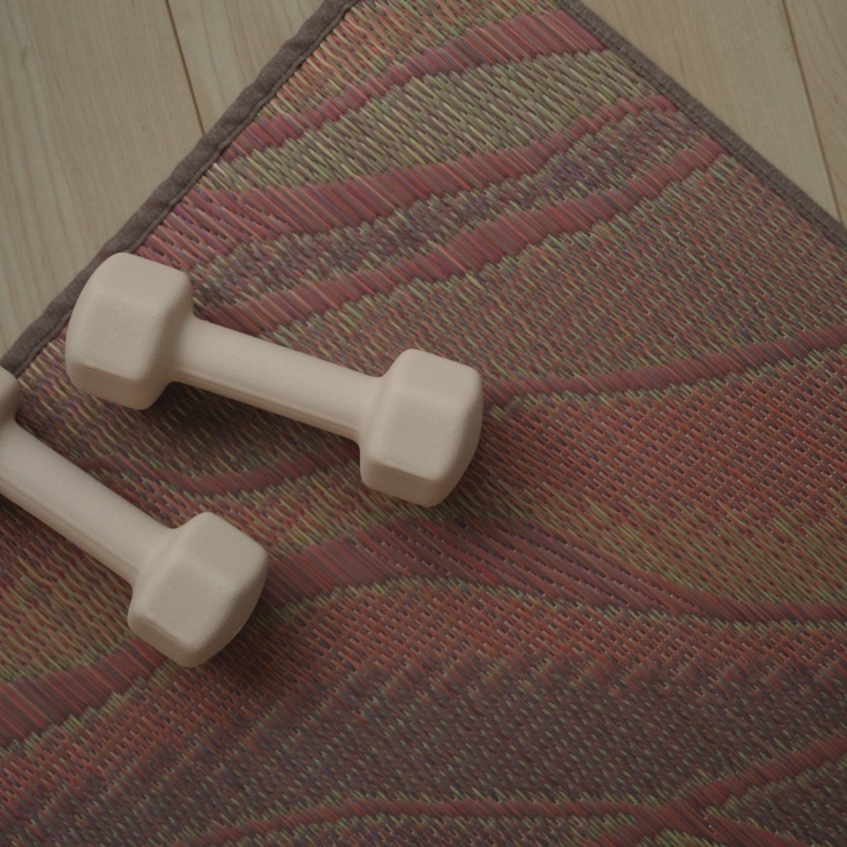 Close-up of the Japanese Tatami Yoga Mattress "Marble" Pink with dumbbells, highlighting the flowing woven pattern.