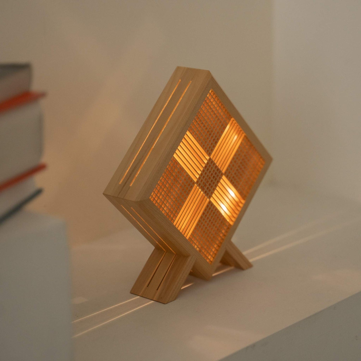 Lit Japanese table lamp Kanata projecting a mystical X-shaped shadow art, creating a serene wabi sabi atmosphere on a Japandi console table.