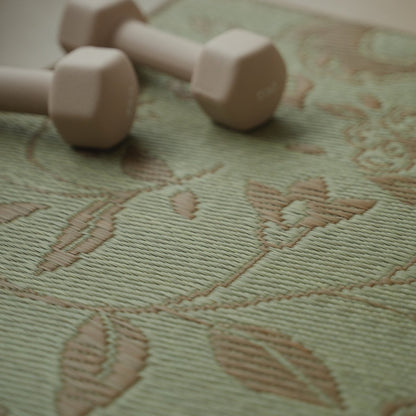Close-up of the botanical pattern on Japanese Tatami Yoga Mattress "Sarasa" Beige with natural rush grass texture and a nearby dumbbell.