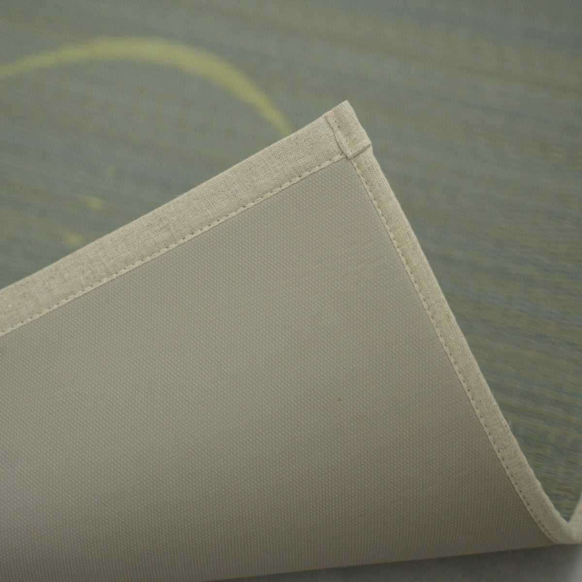 Grijze Japanse Tatami Yogamat "Maan" licht opgetild aan de hoek, waardoor de schone randen en de antislip TPE-onderkant voor een veilige training zichtbaar worden.