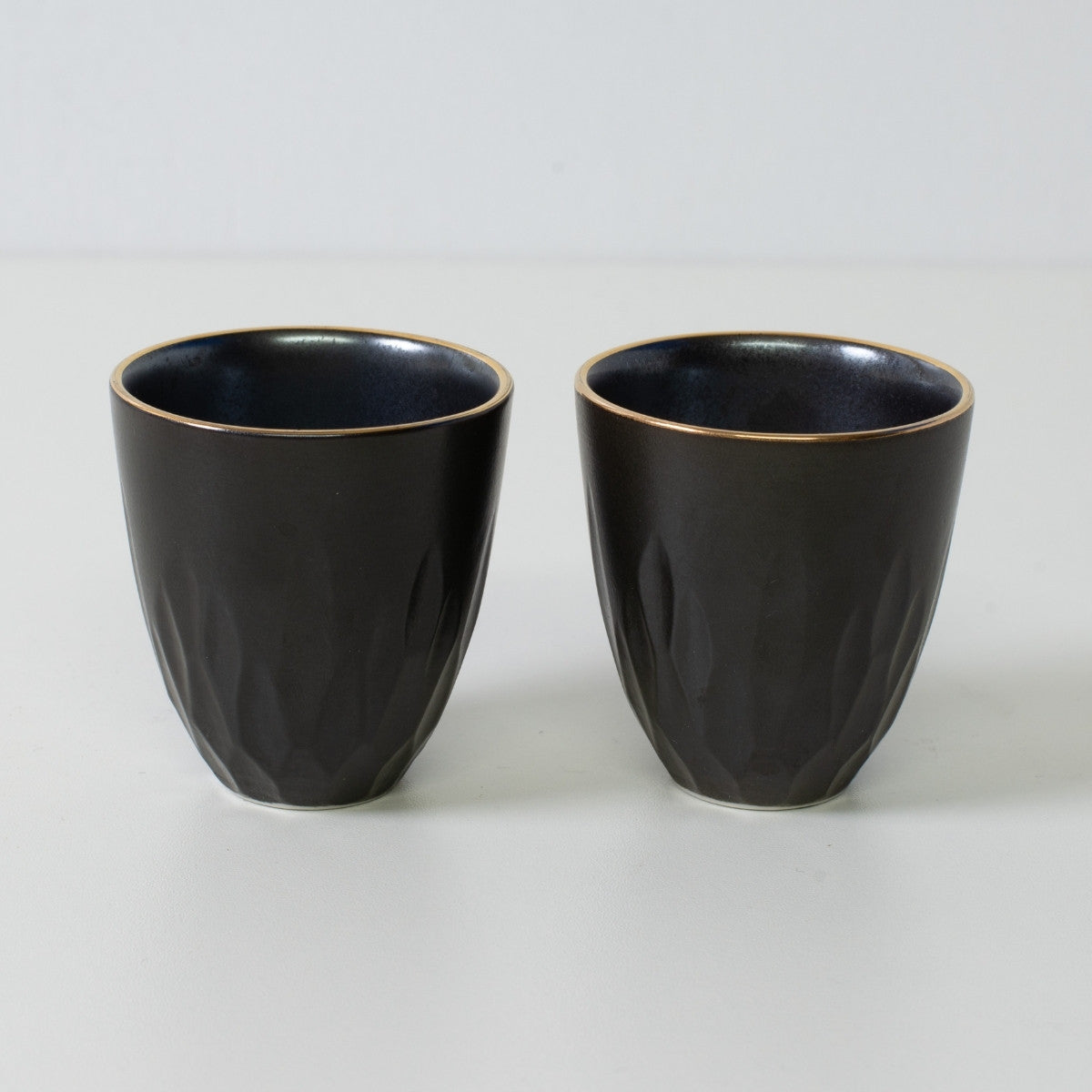 Tasses à saké en porcelaine noire à motifs floraux sculptés - Deux tasses à saké noir mat avec bords dorés et surface texturée