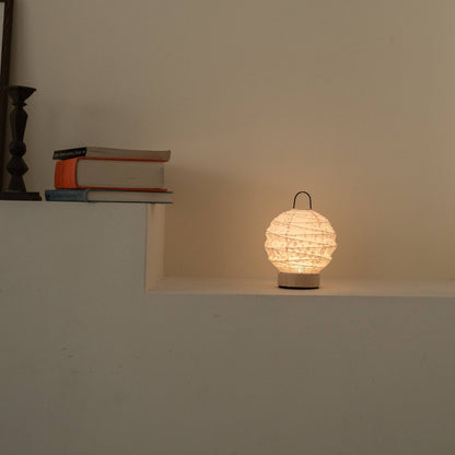 Lit round Japanese paper table lamp "Yuhi" Sakura casting a soft glow as an ambient lamp on a white Japandi style console.