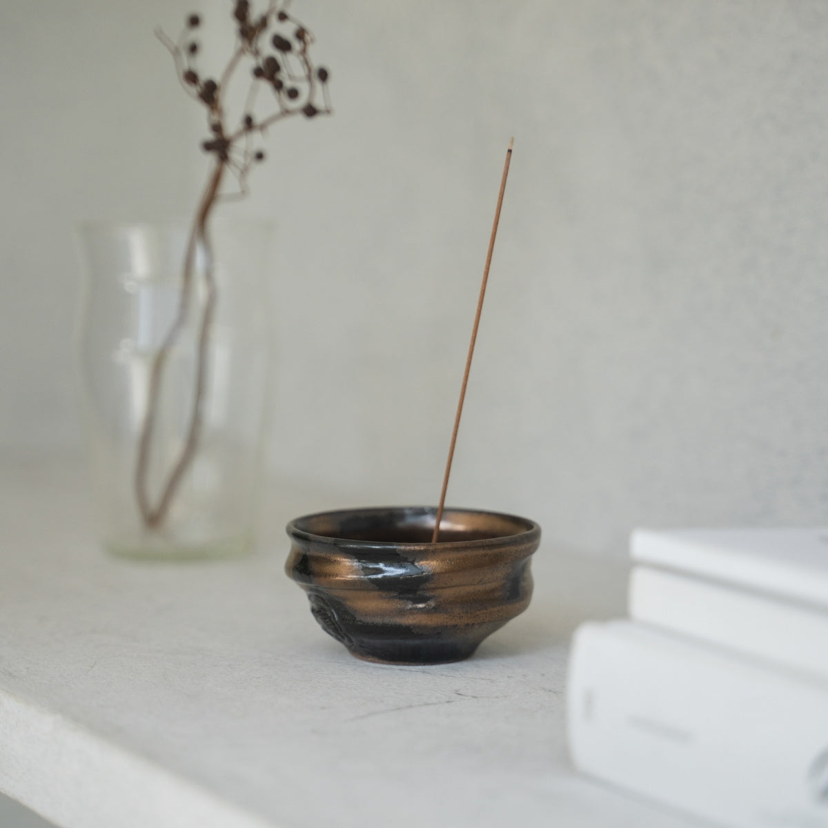 Gouden en zwarte diepe kom Japanse wierookbrander met gouden en zwarte glazuur op een heldere plank, voegt wabi-sabi toe aan een woonkamer.