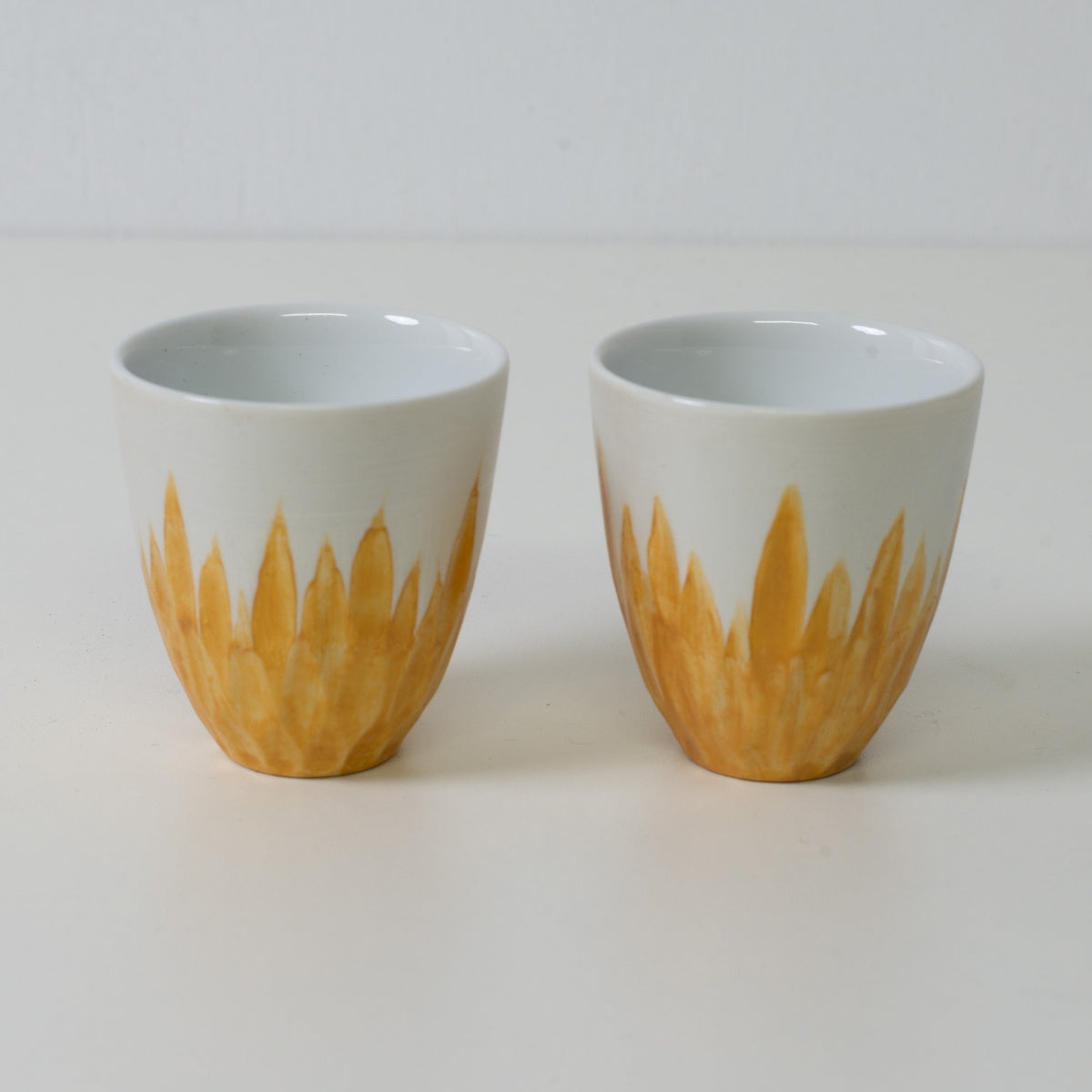 Guld-blomstrede sake-kopper i hvidt porcelæn – To japanske sake-kopper med et blomsterdesign i guld på bunden