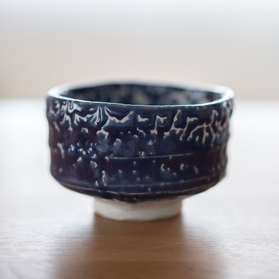 Profilbillede af den håndlavede japanske Matcha-skål "Midnight Blue Kairagi" på et træbord, der viser den rå, teksturerede yderside af den traditionelle Kairagi-glasur.