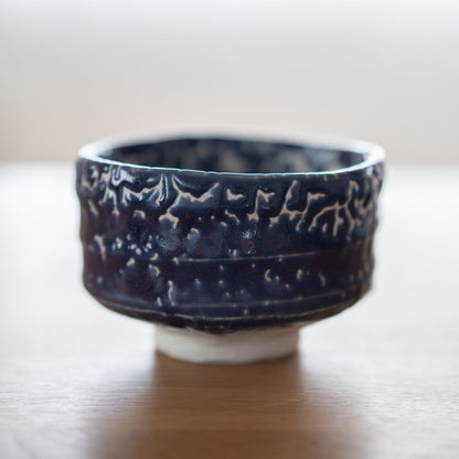 Profilbillede af den håndlavede japanske Matcha-skål "Midnight Blue Kairagi" på et træbord, der viser den rå, teksturerede yderside af den traditionelle Kairagi-glasur.