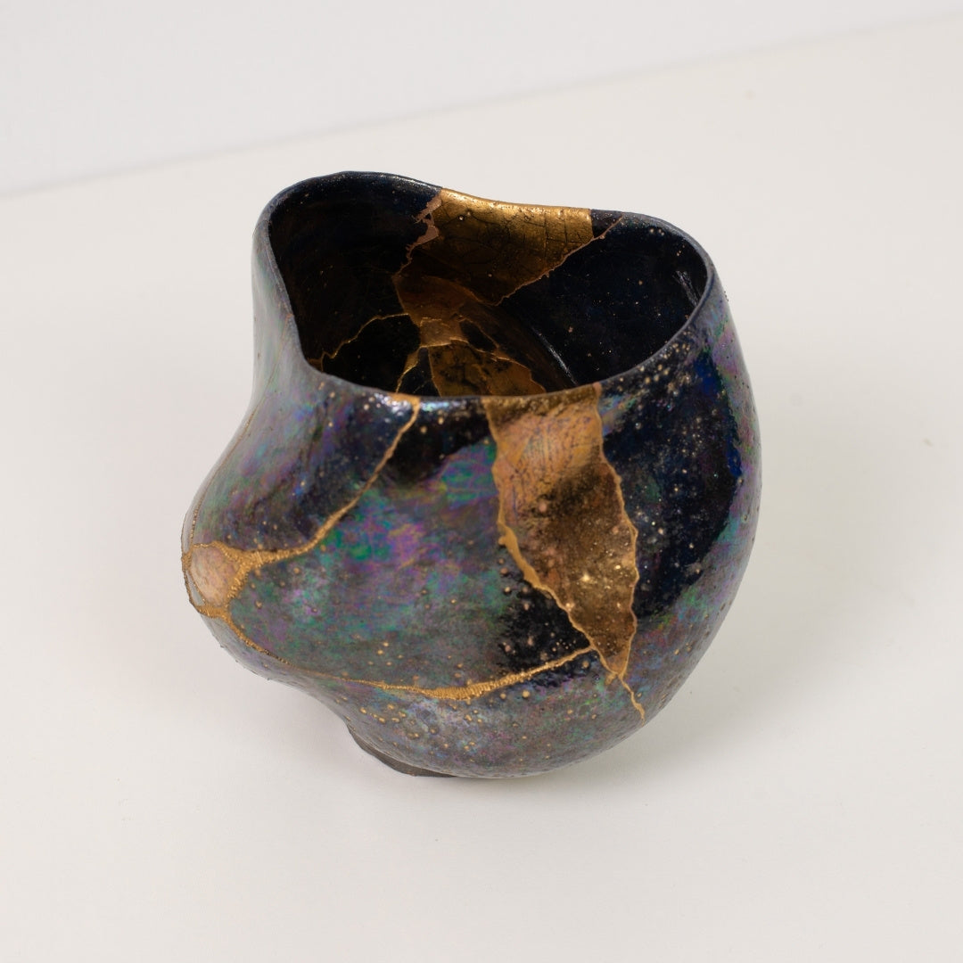 Close-up van een iriserende kintsugi matcha-kom met gouden lijnen die de traditionele wabi-sabi-kunst vieren