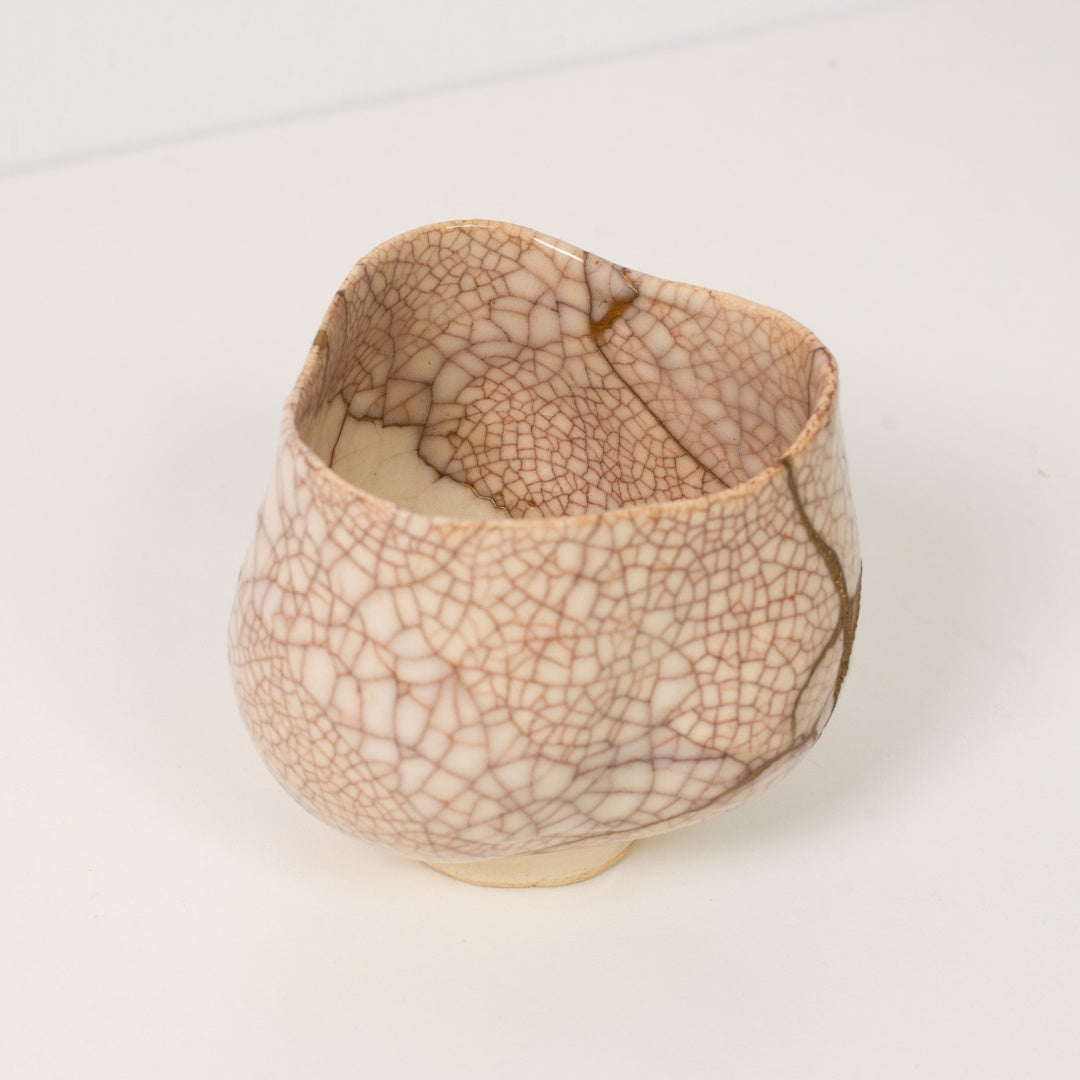 Højt vinkelbillede inde i en hvid krakeleret kintsugi matcha-skål, der afslører dramatiske gyldne reparationer, der legemliggør wabi sabi