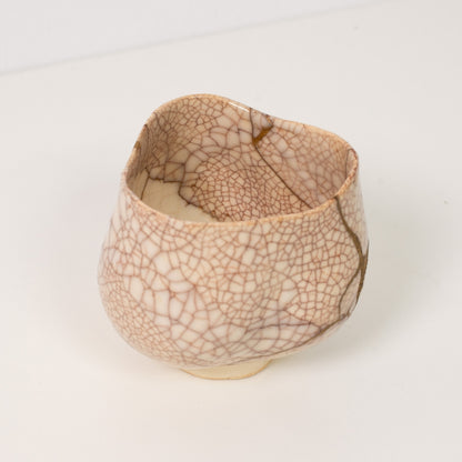 Højt vinkelbillede inde i en hvid krakeleret kintsugi matcha-skål, der afslører dramatiske gyldne reparationer, der legemliggør wabi sabi