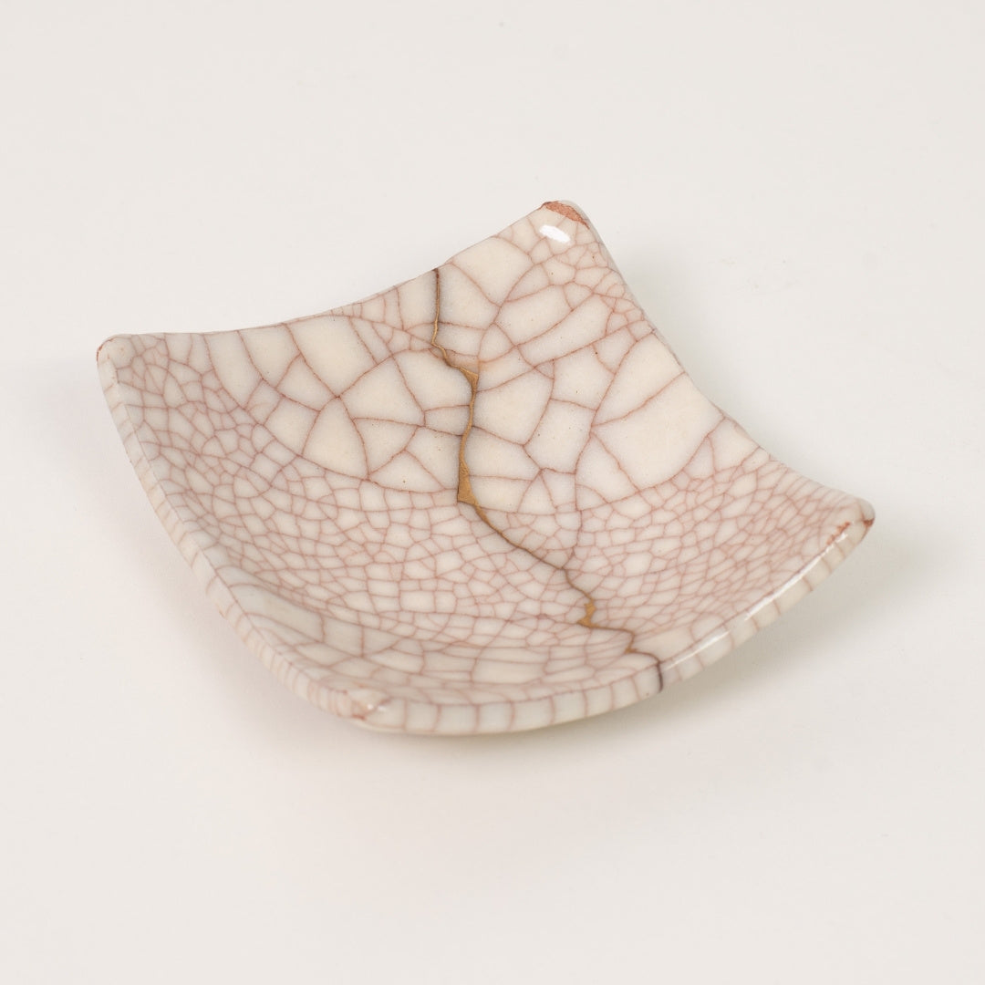 High angle view of a white square kintsugi plate highlighting the gold repair and crackle glaze of this kintsugi pottery