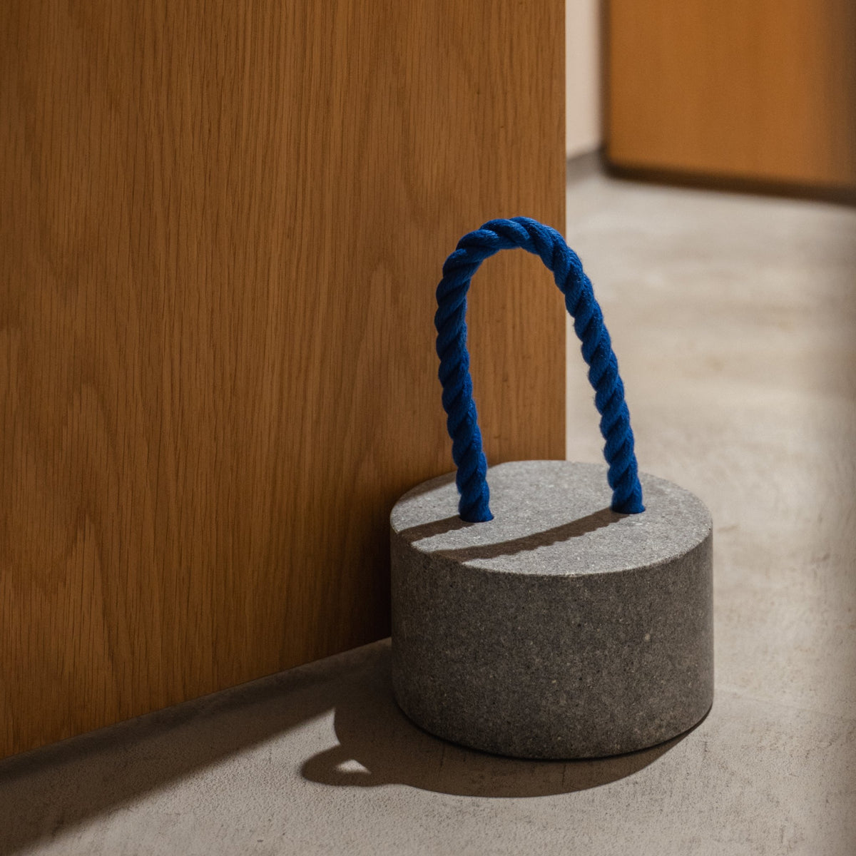 Japanese Aji Stone Doorstop "FUJ" in natural stone styled in a entryway setting, entryway scene view.