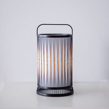Eine japanische Bambus-Stehlampe auf einem weißen Tisch.