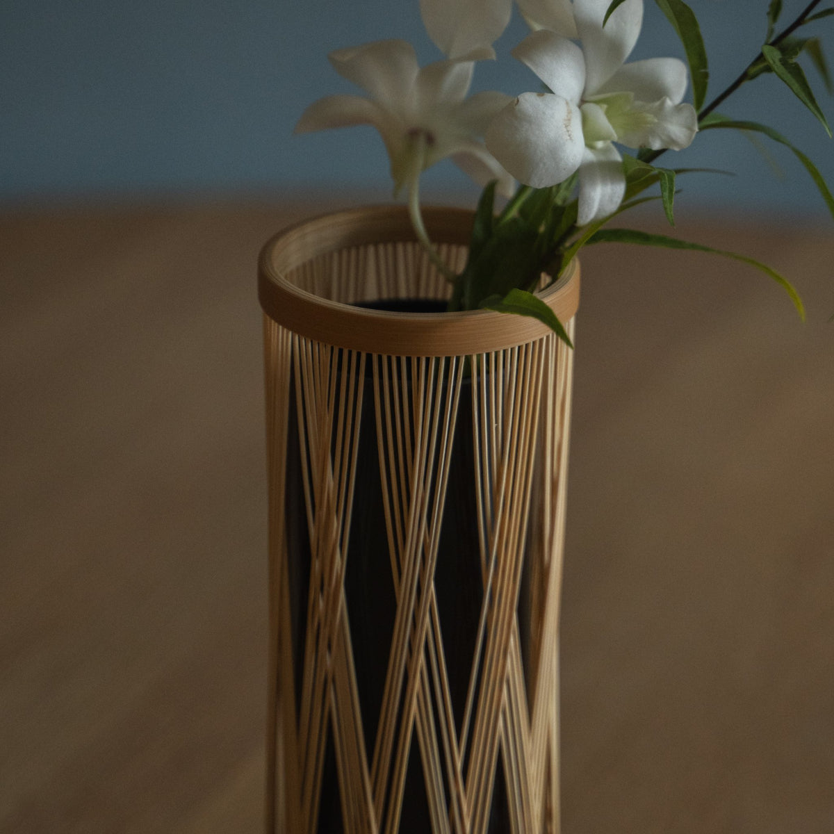 Vase à fleurs en bambou japonais « Branche entrelacée » marron, mis en scène dans un intérieur.