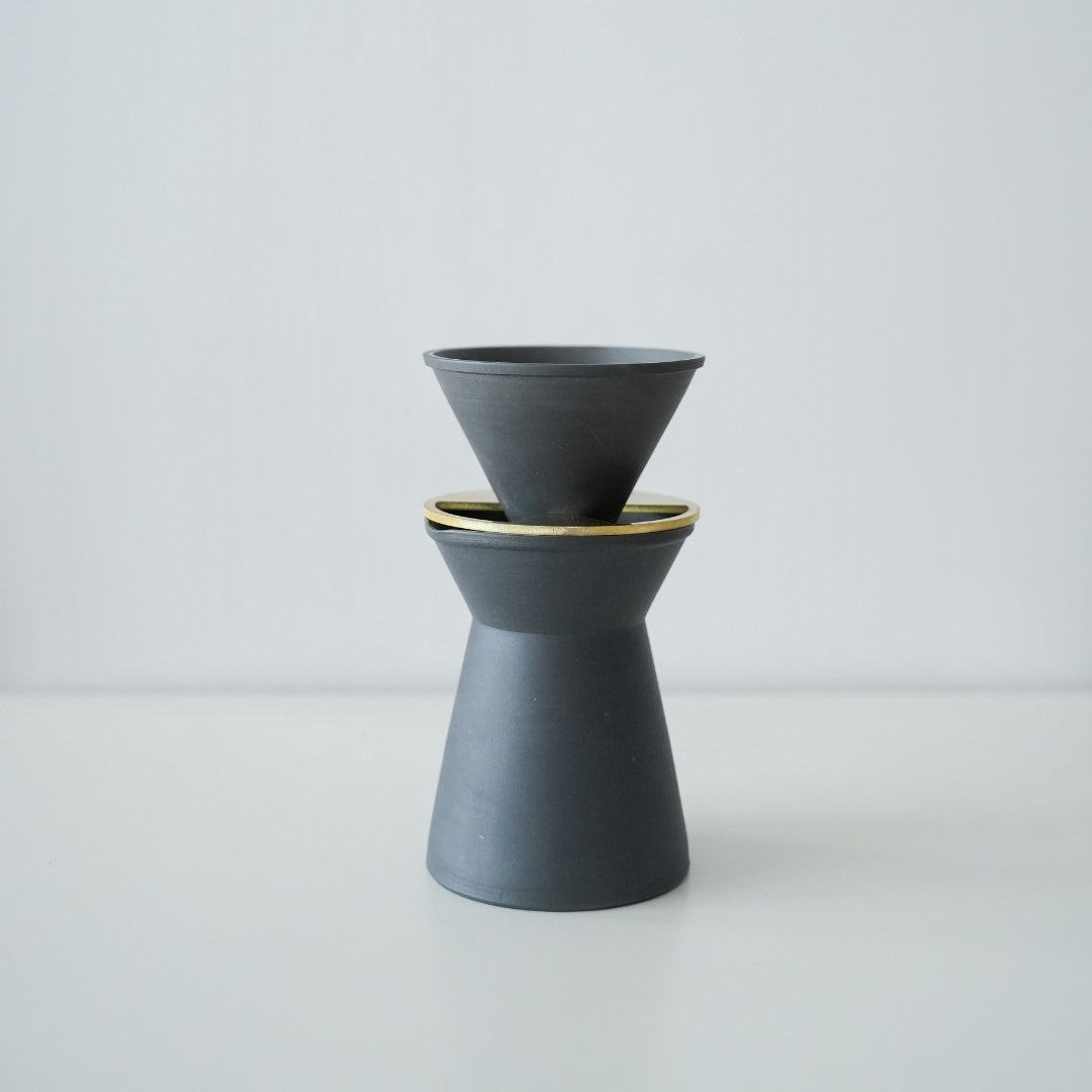 Et sæt minimalistisk sort-hvidt Banko-stel kaffeserver og drypper på et køkkenbord i træ.