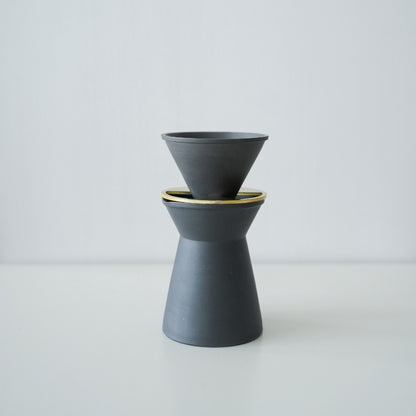 Et sæt minimalistisk sort-hvidt Banko-stel kaffeserver og drypper på et køkkenbord i træ.
