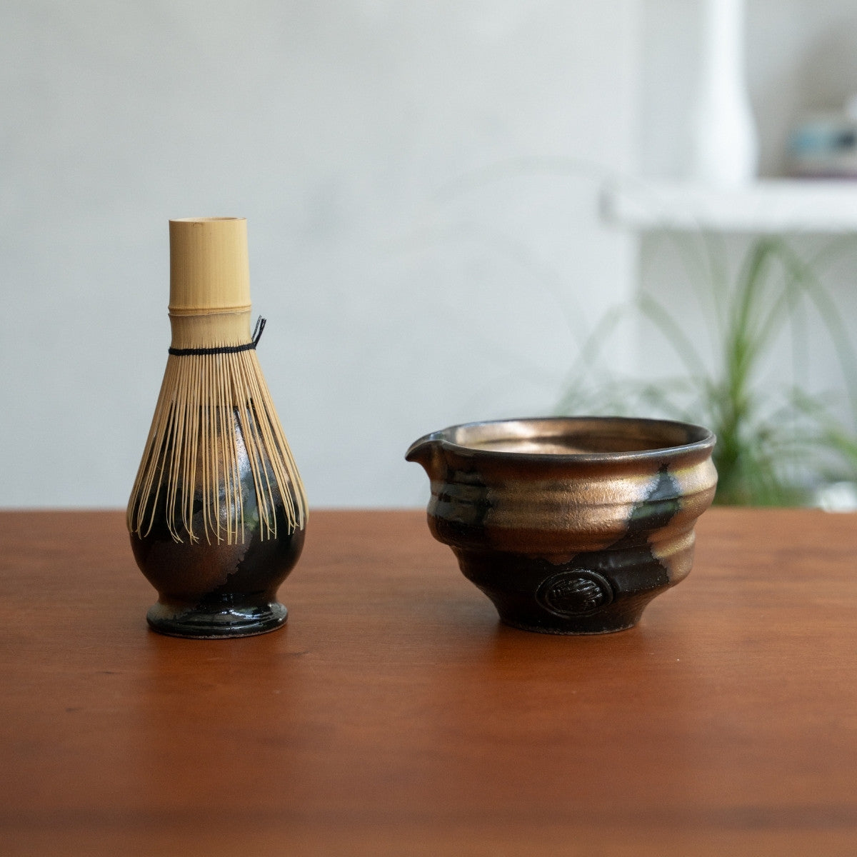 Support de fouet à matcha japonais et bol à matcha avec bec verseur sur une table en bois, gardant les outils prêts pour une routine de bien-être quotidienne.