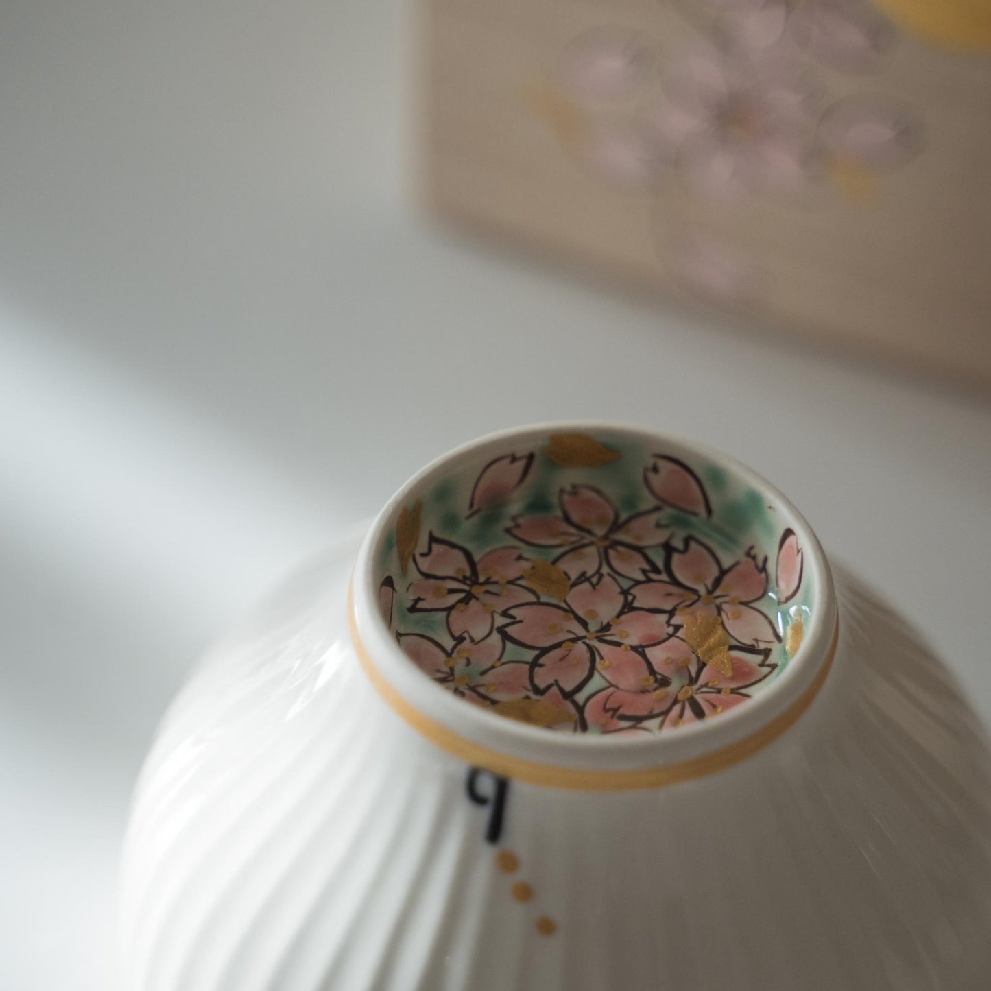 Opslået hvid matcha-skål med lyserøde kirsebærblomster malet indeni foden.