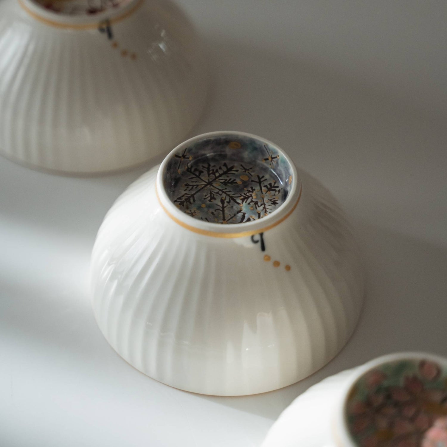 Detaljeret visning af fodringen på en hvid keramisk matcha-skål med håndmalede iskrystaller.