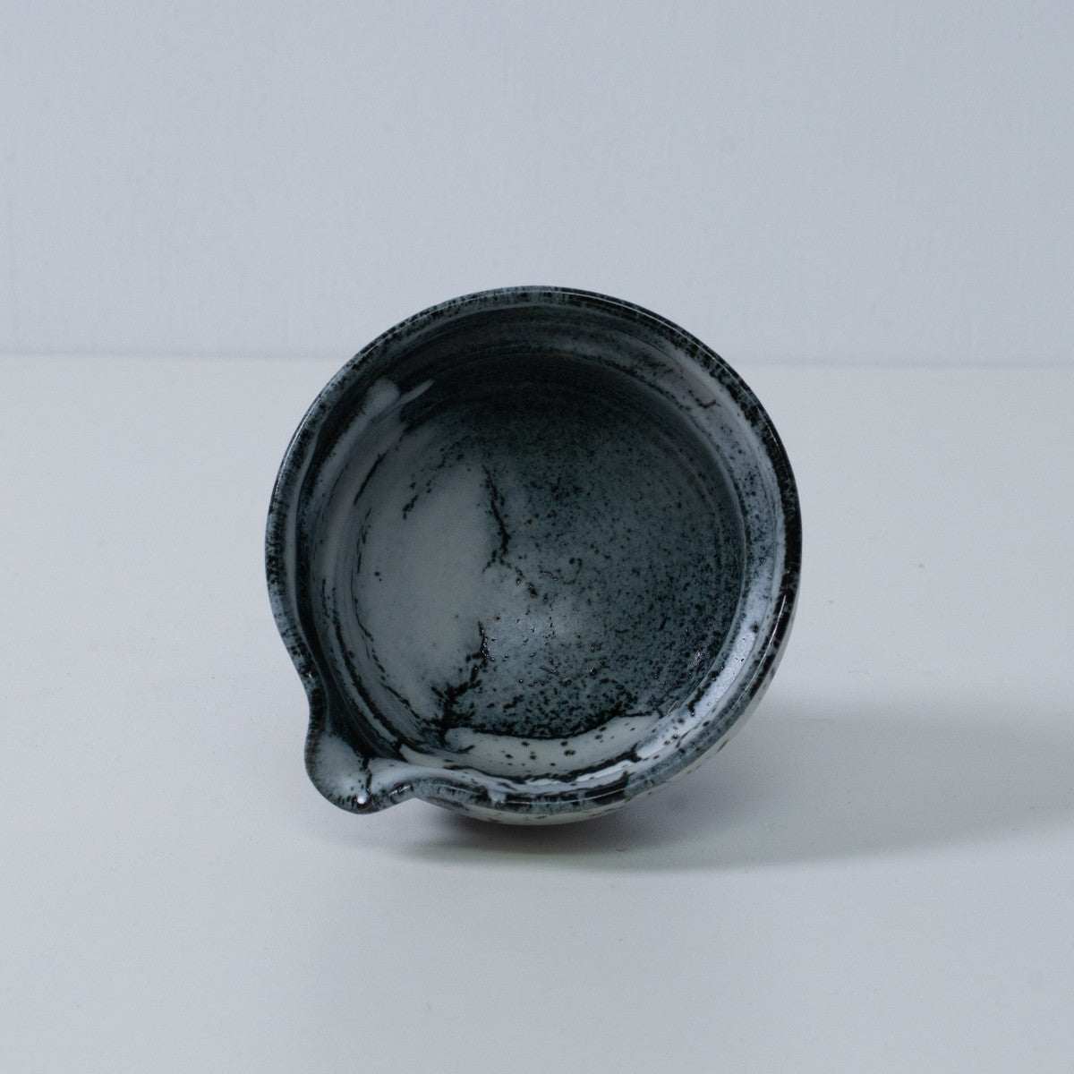 Inside view of a Japanese matcha bowl with spout "Creative Cloud" pottery, showing the white and black gradient glaze, Japan.