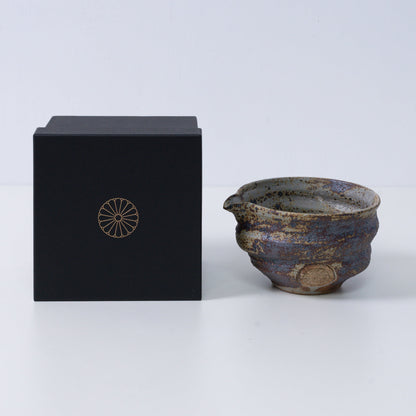 Rustic brown Japanese matcha bowl with spout "Sakigake" pottery next to a black gift box with a gold chrysanthemum crest, made in Japan.
