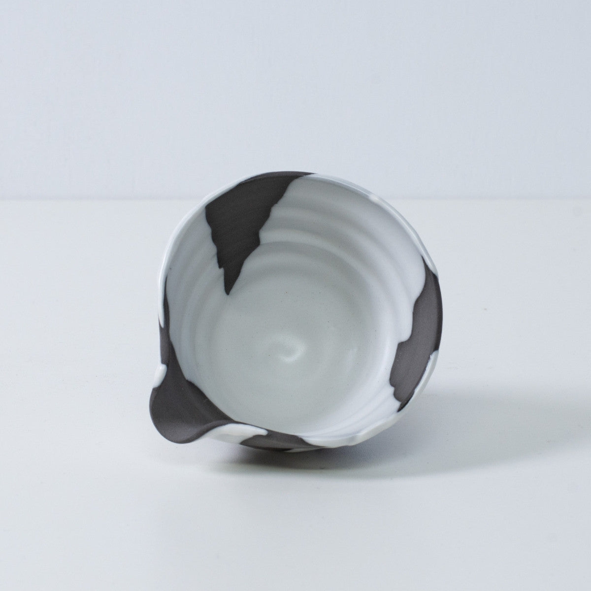 Inside view of a Japanese matcha bowl with spout "White Flow" pottery, showing the white and black glaze, made in Japan.