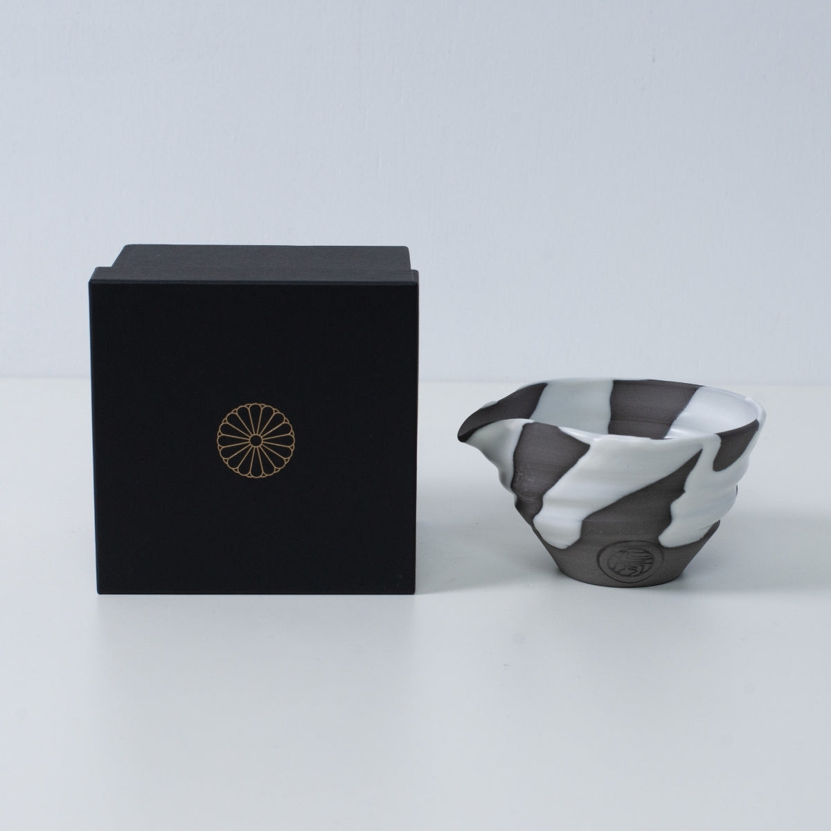 Bol à matcha japonais avec bec verseur "White Flow" en céramique à côté d'une boîte cadeau noire avec un blason de chrysanthème doré, fabriqué au Japon.