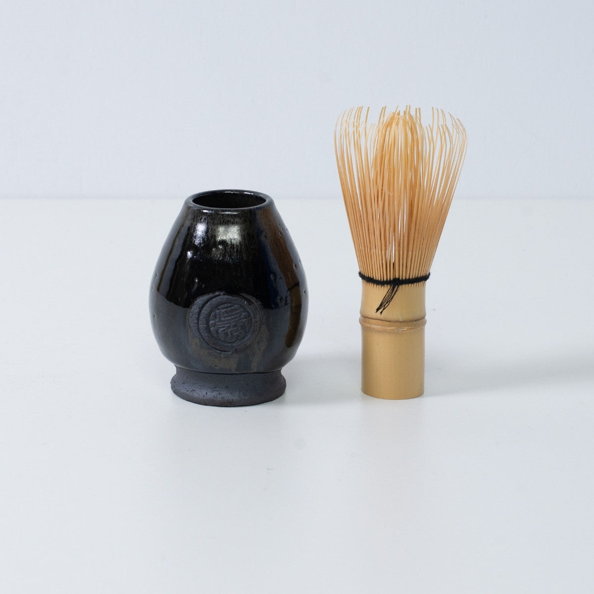 Deep blue Japanese matcha whisk stand "Dignity Blue" pottery standing next to a traditional bamboo matcha tea whisk chasen, Japan.