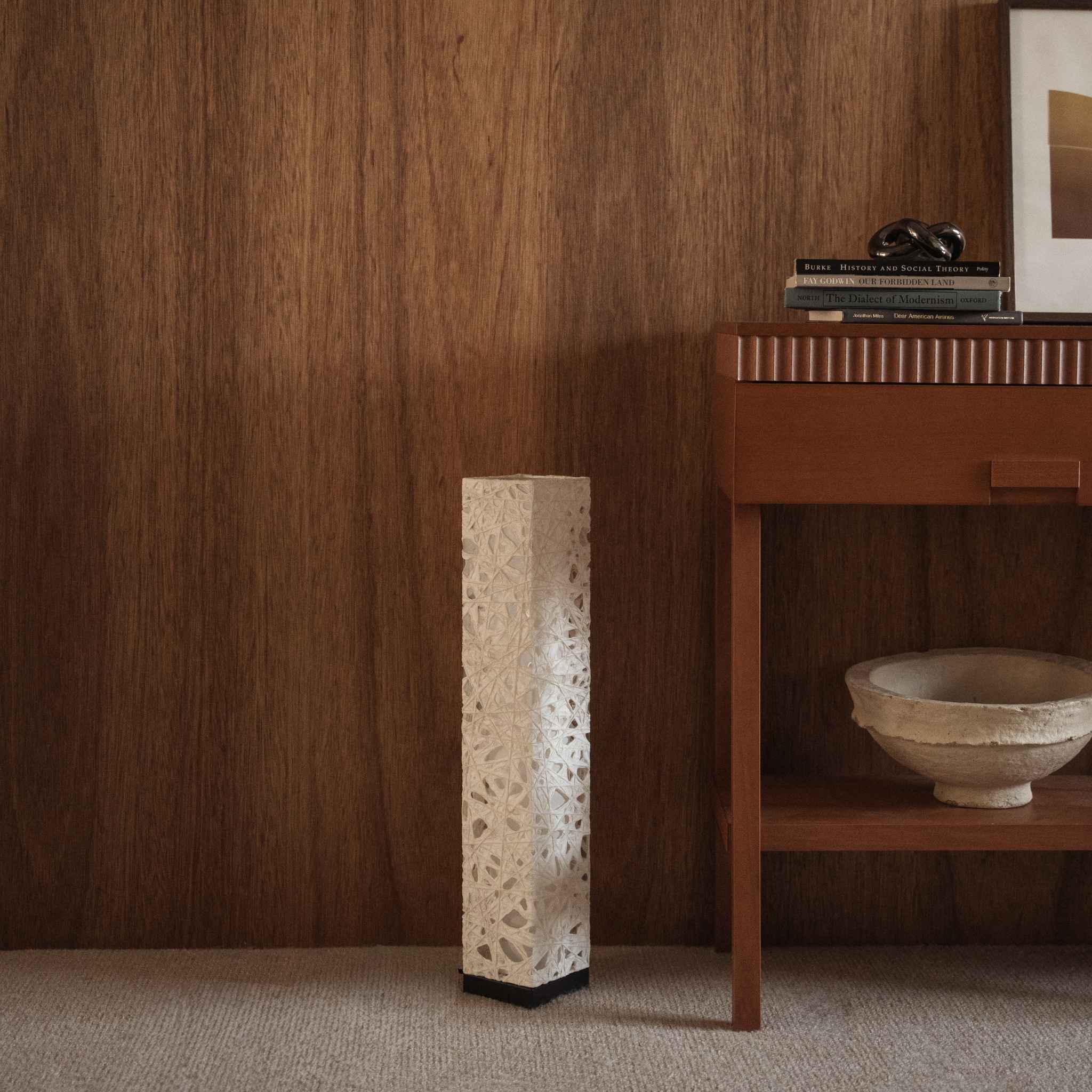 "Lampe sur pied en papier blanc Me Look 02, éteinte, posée sur un tapis devant un mur en bois près d'une console."