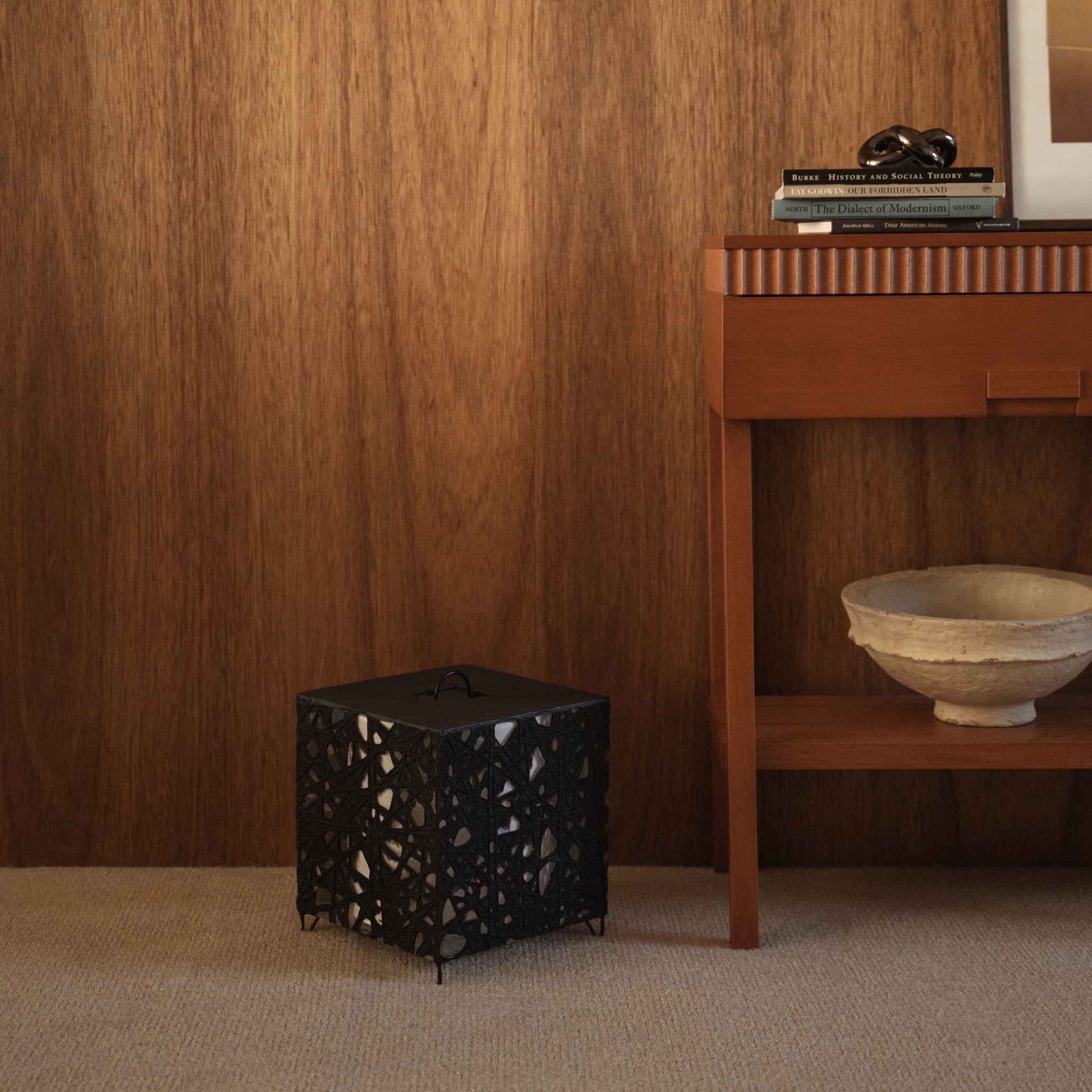 Lampe sur pied cubique en papier noir Me-Look 03 posée sur un tapis beige devant un mur en bois sombre dans un salon