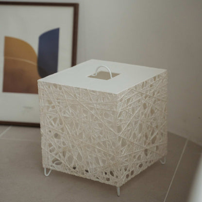 "Lampe de sol japonaise cube blanc non allumé Me Look 03 posée sur un sol carrelé beige à côté d'une estampe encadrée"