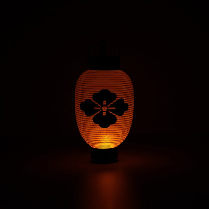 Een gloeiende bloemdiamant Japanse lantaarn die een donkere ruimte verlicht met een zacht en meditatief oranje licht.