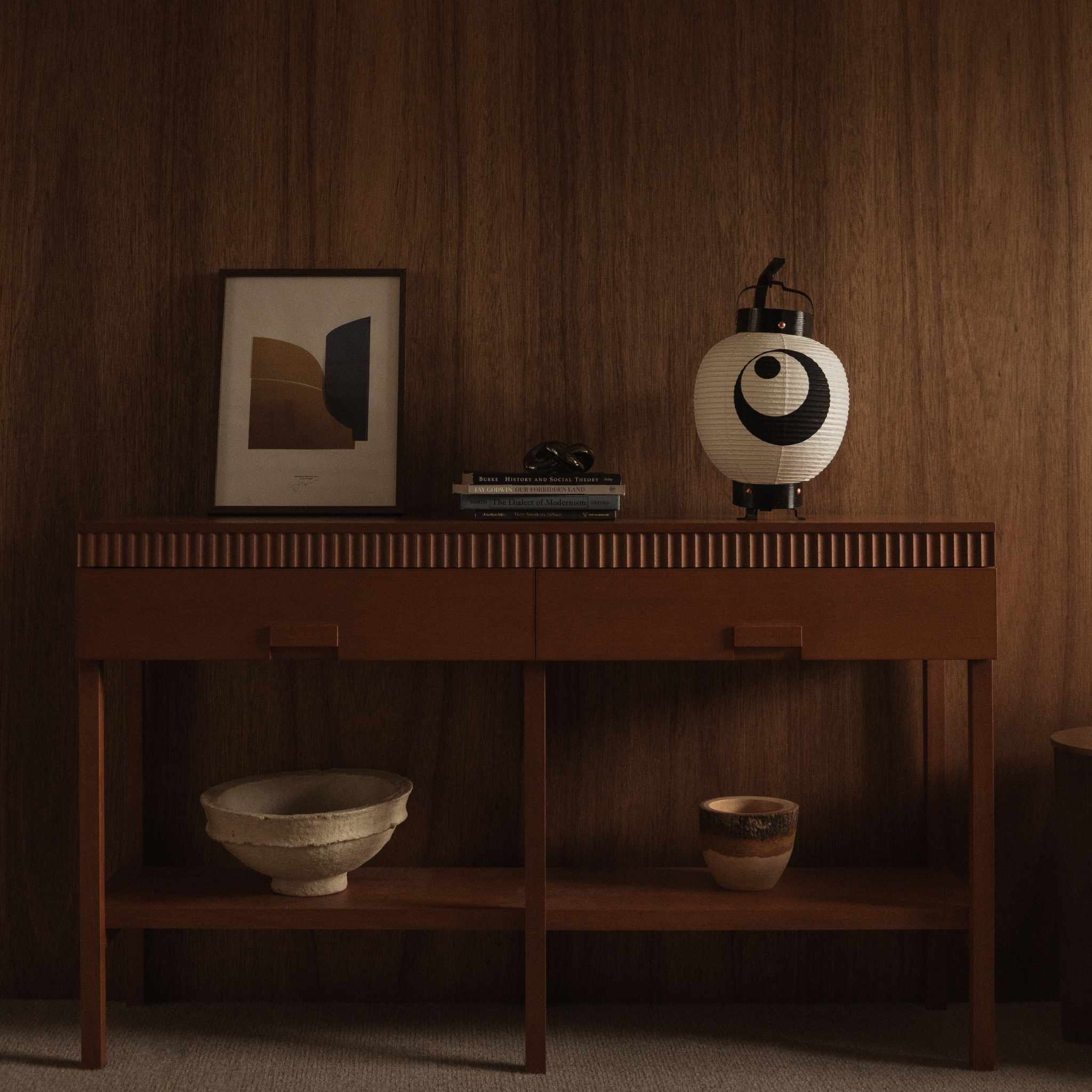 Onverlichte witte Japanse papieren lantaarn 'maan en ster' model geplaatst op een houten console tafel met ingelijste kunst als interieurdecoratie
