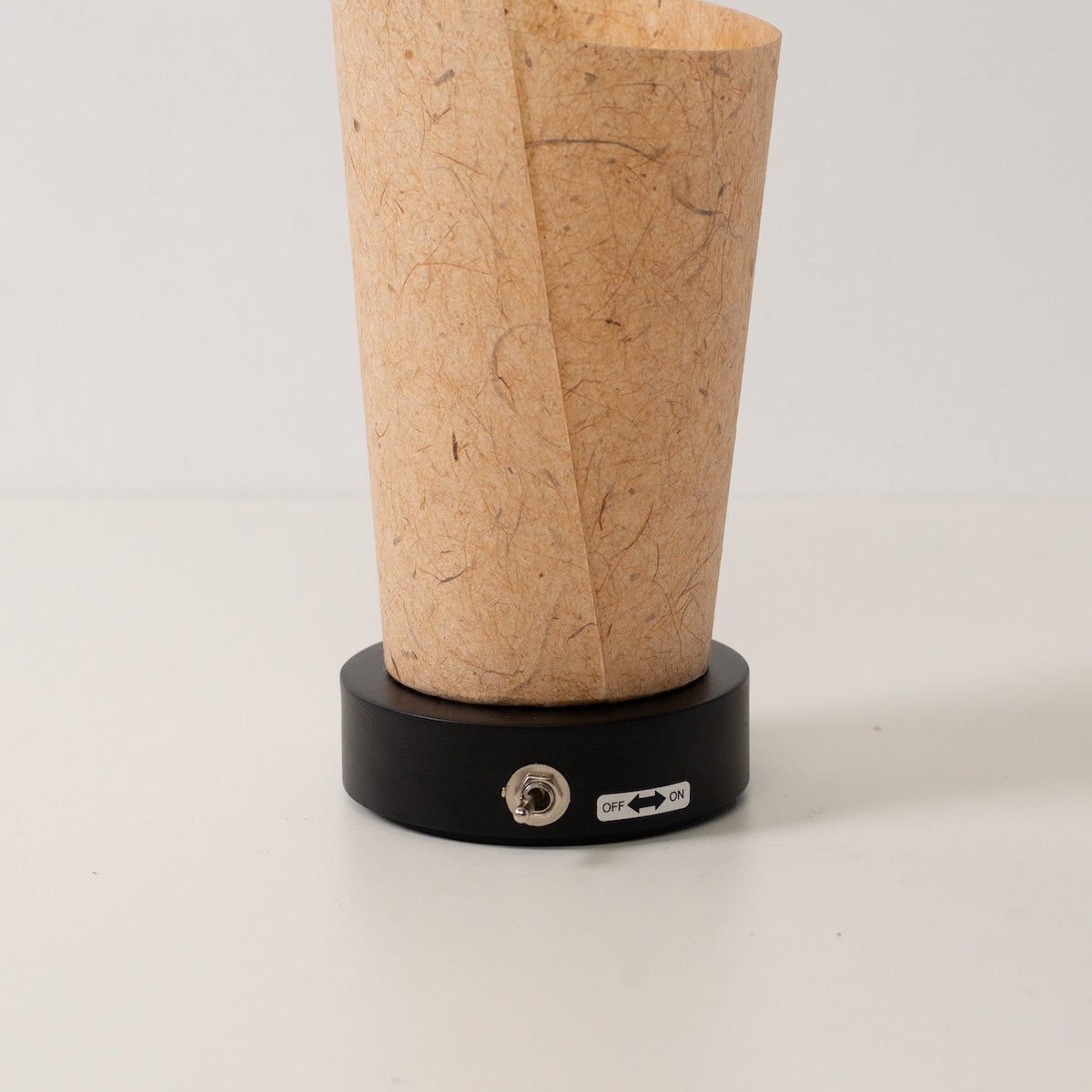 "Lampe de table japonaise en papier « Maki » écorce de cèdre, marron, bois - gros plan de la base noire et de l'interrupteur à bascule de la lampe sans fil."
