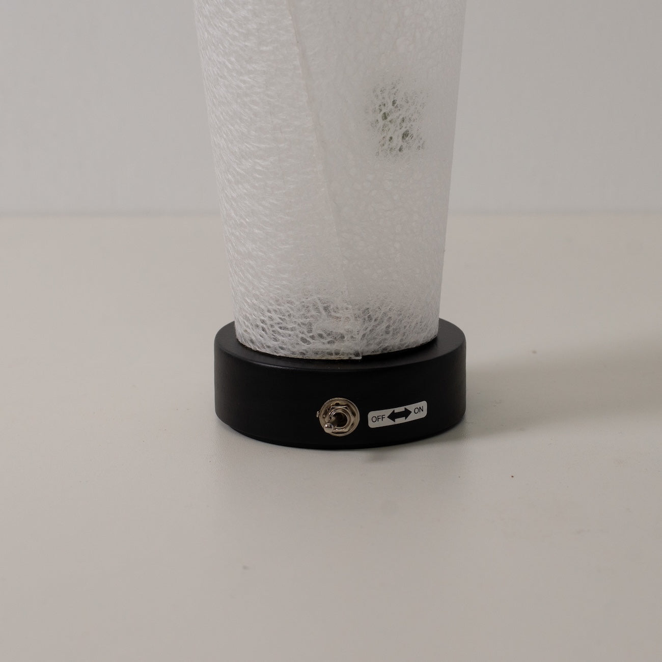"Lampe de table japonaise en papier « Maki » feuille d'érable, blanc, bois - gros plan de la base noire et de l'interrupteur à bascule de la lampe sans fil."