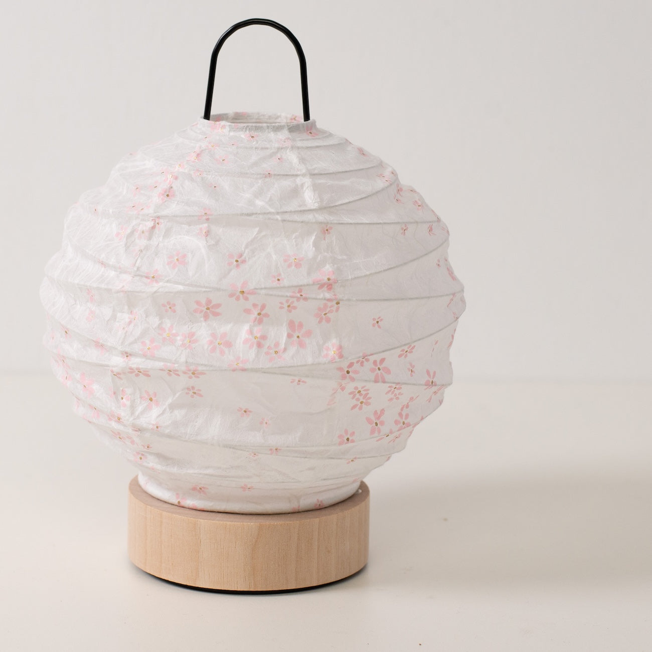 Japanese Paper Table Lamp "Yuhi" Sakura, white, Mino Washi paper and wood - angled view of unlit round paper lamp and solid base.