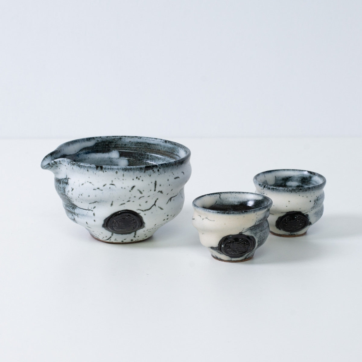 White and black Japanese sake set "Creative Cloud" pottery featuring a katakuchi sake carafe pitcher and two small sake cups, made in Japan.