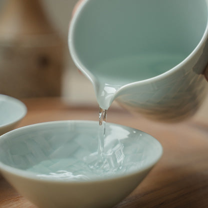 Verser à la main depuis une carafe à saké japonaise bleu glacier dans une tasse à saké texturée, rehaussant un dîner spécial.
