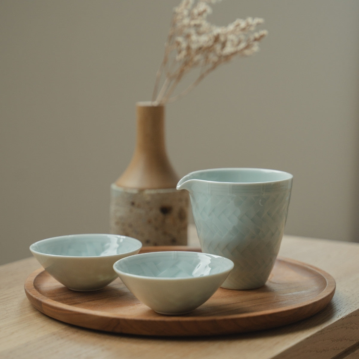 Ensemble de saké en porcelaine arita bleu glacier du Japon sur un plateau en bois, pour une expérience culinaire moderne et réfléchie.