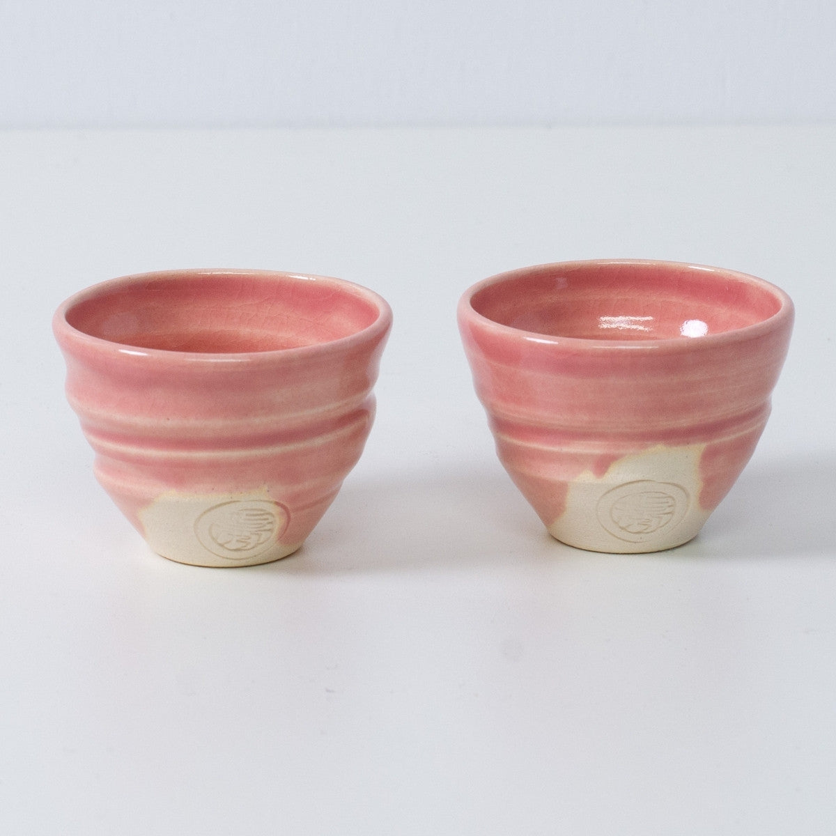 Two Japanese sake cups ochoko "Omuro Cherry" pink pottery from Japan, featuring an engraved artisan seal on the front.