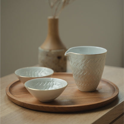 Weiße japanische Arita-Porzellan-Sake-Karaffe und Sake-Becher aus Japan auf einem Holztablett, arrangiert für ein achtsames Esserlebnis mit Gästen.