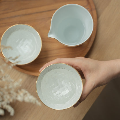 Hand hält eine strukturierte weiße japanische Arita-Porzellan-Sake-Tasse über einem Holzteller, die Sake-Liebhaber zu einem ruhigen Abend einlädt.