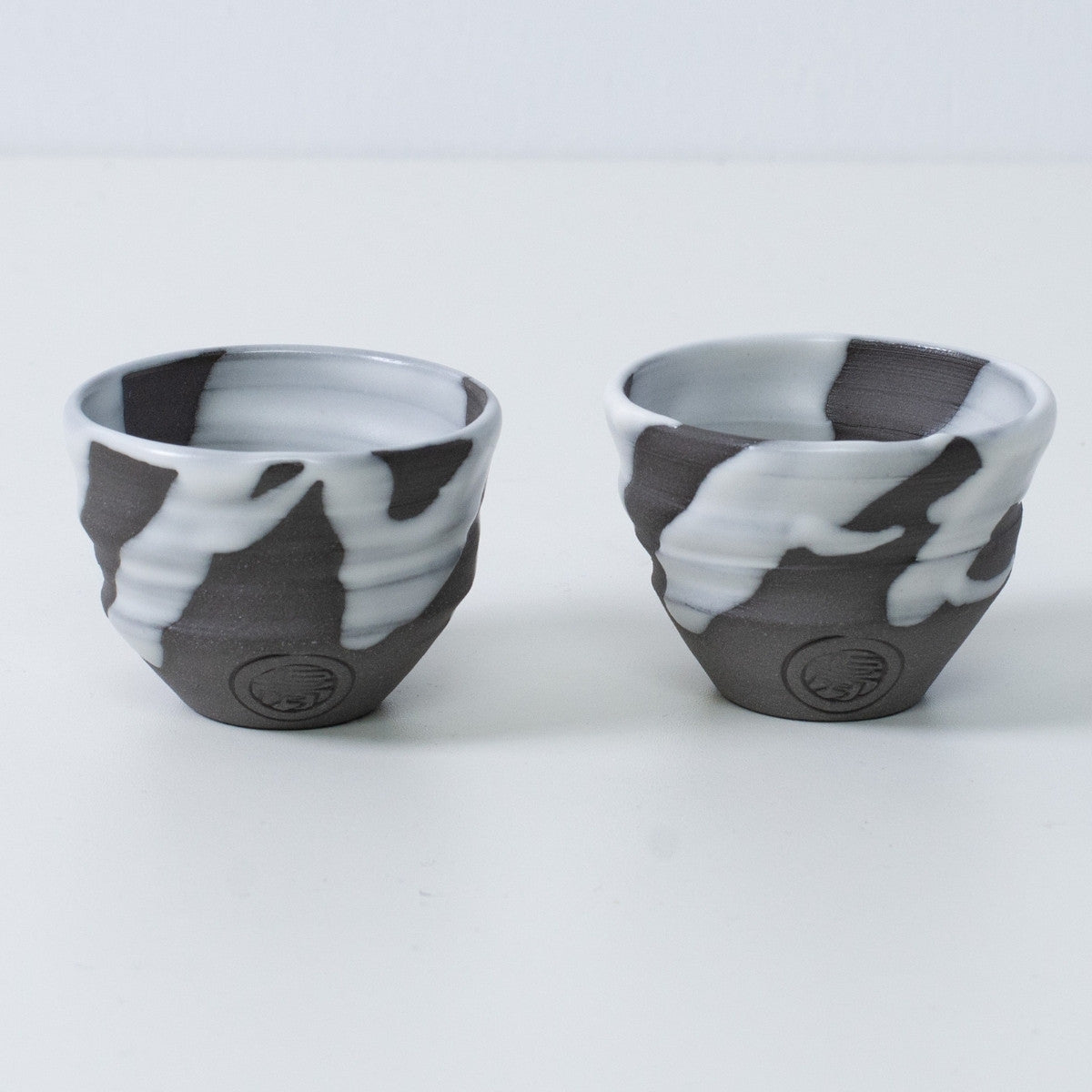 Two Japanese sake cups ochoko "White Flow" pottery from Japan, featuring an engraved artisan seal on the front of each cup.