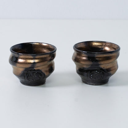 Zwei japanische Sake-Becher Ochoko "Zen" aus Gold und schwarzer Keramik aus Japan, mit eingraviertem Handwerkersiegel auf der Vorderseite.