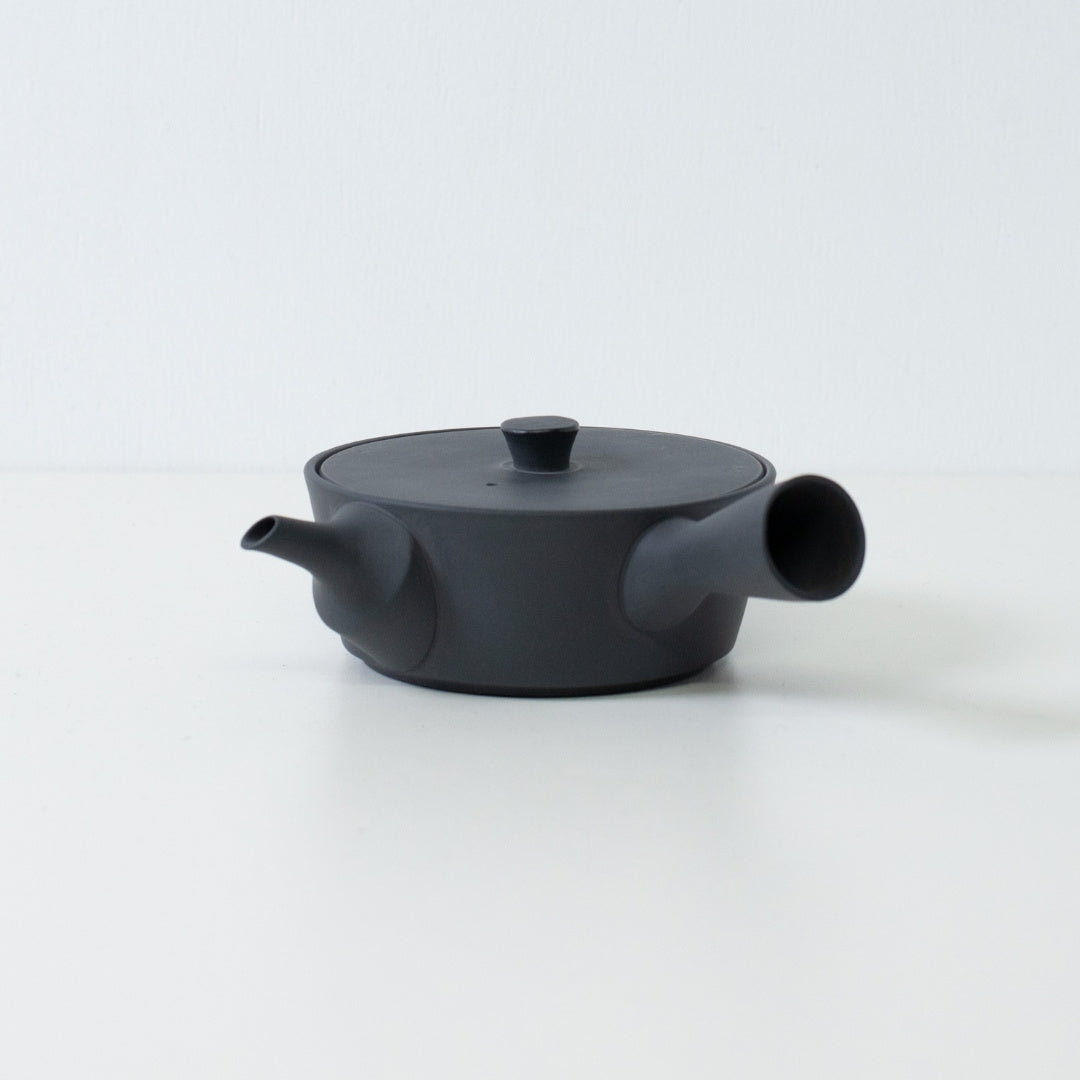 Lav profil flad sort japansk tekande sencha-stil med et sidehåndtag isoleret på en hvid baggrund.