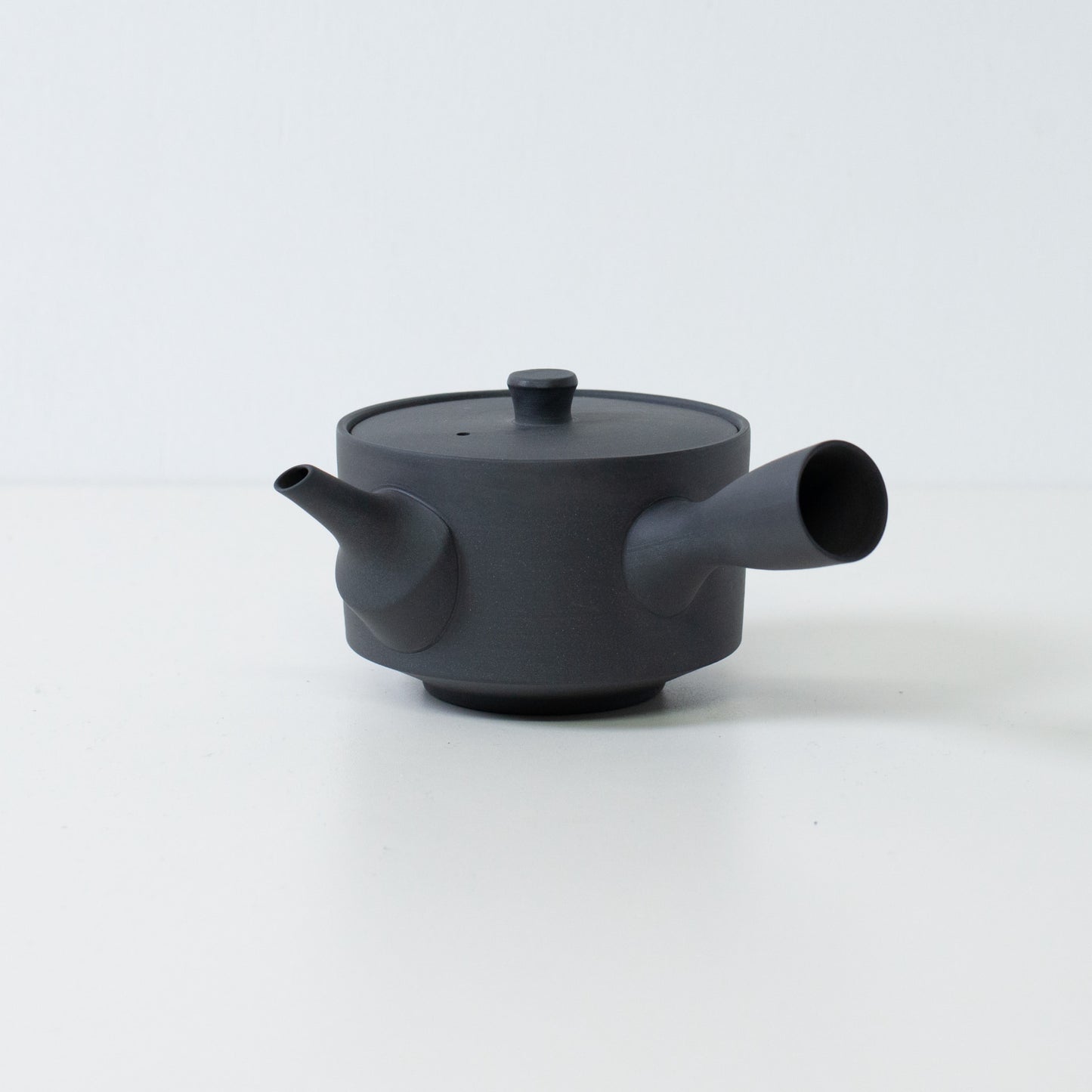 Sidevisning af en sort japansk sencha tekande med et sidehåndtag og låg på en hvid baggrund.