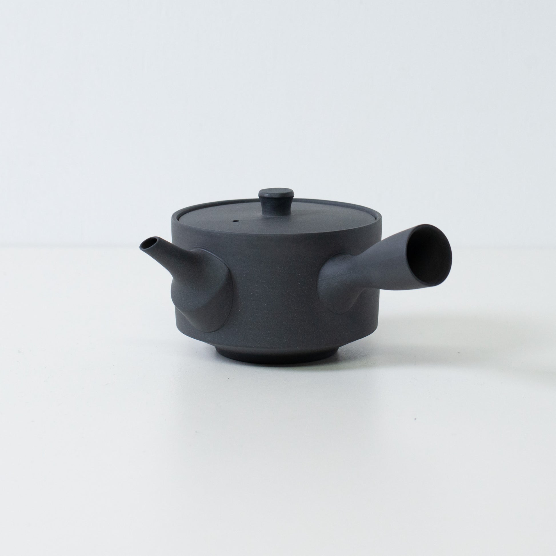 Sidevisning af en sort japansk sencha tekande med et sidehåndtag og låg på en hvid baggrund.